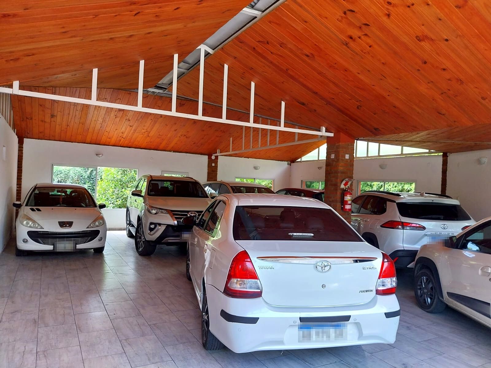 Salón cubierto con autos estacionados bajo un techo de madera